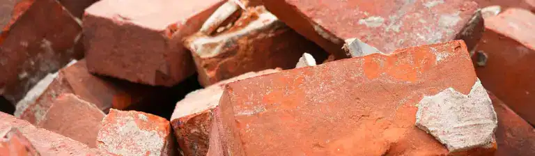 Cracked red bricks stacked together, background for construction or renovation projects.