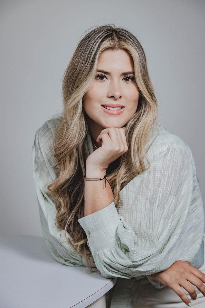 A woman with long blonde hair in a pose for a business profile image.
