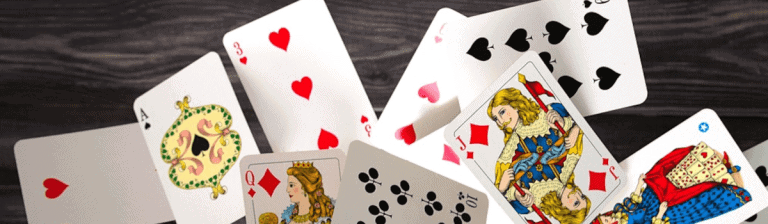Playing cards spread out on a dark wooden surface, featuring the Queen of Diamonds, Jack of Hearts, and Ace of Spades, representing games, strategy, and entertainment.