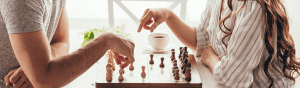 AI image of two women playing chess on opposite sides of the board. Only their shoulders, arms, and hands are visible as they determine their next move
