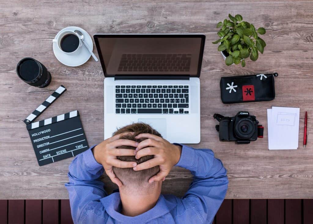 Overhead view of a person at a virtual office workspace with a laptop, camera, coffee, and creative tools for SEO and virtual office services.