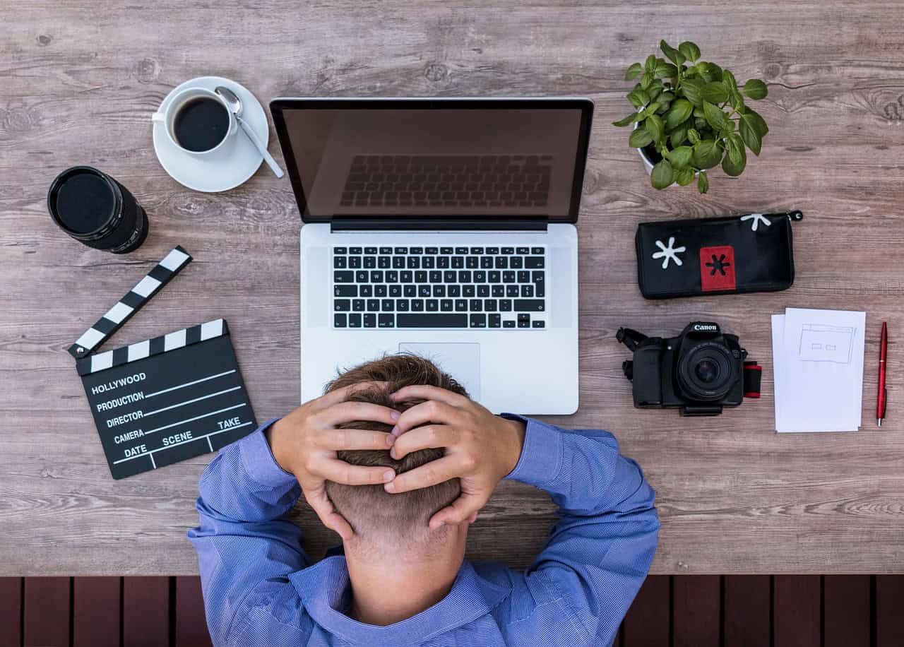 Overhead view of a person at a virtual office workspace with a laptop, camera, coffee, and creative tools for SEO and virtual office services.