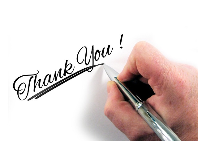 Image of a hand writing Thank You in cursive.