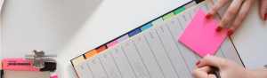 Close-up partial image of a woman's hands writing on a planner page.